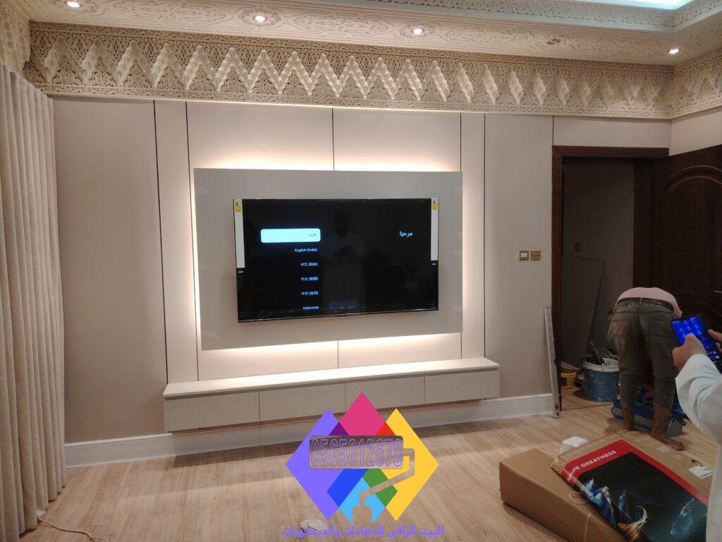 ديكور شاشة عصري بتصميم جداري مدمج يجمع بين شرائح بديل الخشب العمودية ولوح خلفي من بديل الرخام الأبيض.